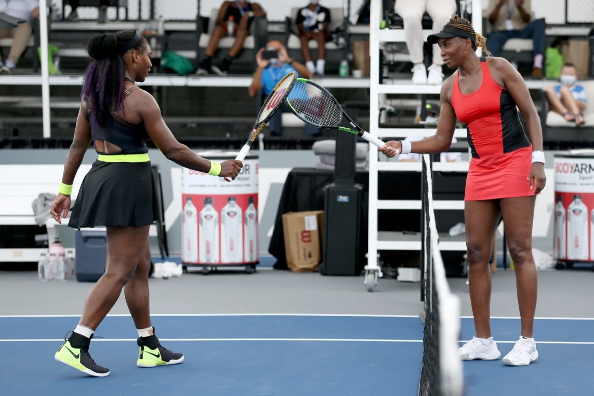 Serena Williams (L) and Venus Williams touch rackets after Serena Williams defeated Venus Williams